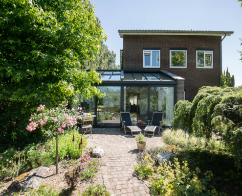Een serre aanbouw in antraciet kleur aan een voorheen donker woonhuis